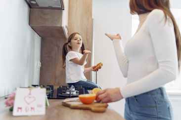 loving mother and daughter blowing kiss on kitchen